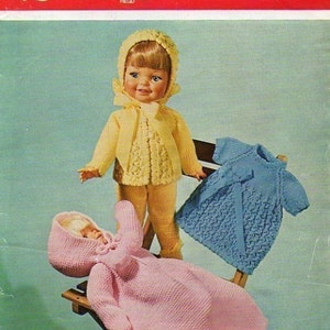 May include: A knitting pattern booklet for a doll's outfit. The cover features a doll wearing a yellow cardigan and a blue dress. The title of the pattern is "Bronte" and the pattern number is 764. The pattern is for double knitting.