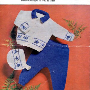 May include: A white knitted baby cardigan with blue snowflake trim, matching blue knitted pants, and a white knitted hat with blue snowflake trim. The pattern number is 1830. The text "Robin Double Knitting to fit 18 to 22 chest" is printed on the page.