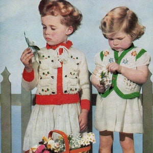 Op de afbeelding: Twee jonge meisjes dragen gebreide truien met katten- en bloempotmotieven. Het meisje links draagt een witte trui met rode bies en het meisje rechts draagt een witte vest met groene bies. Beide meisjes houden bloemen vast. De afbeelding bevat de tekst "Kittens and Flower Pots!" en "in Patons Moorland Double Knitting".