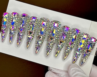 Peut inclure: Ensemble de dix faux ongles en forme de stiletto, incrustés de cristaux irisés.