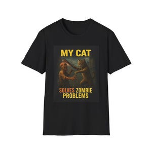 Könnte beinhalten: Schwarzes T-Shirt mit einem humorvollen Grafikdesign. Es zeigt eine Katze, die gegen einen Zombie kämpft, mit dem gelben Text "MY CAT SOLVES ZOMBIE PROBLEMS". Das Bild ist mittig auf dem Shirt platziert.