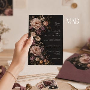K&ouml;nnte beinhalten: Eine schwarze Hochzeitseinladung mit floralen Akzenten, gehalten von einer Hand. Die Einladung enth&auml;lt die Namen Amelia Lane und Joseph Guthrie sowie Hochzeitsdetails. Ein passender Umschlag und florale Designelemente sind ebenfalls sichtbar.