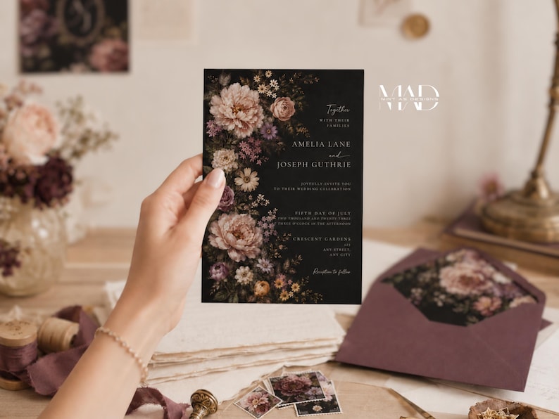 K&ouml;nnte beinhalten: Eine schwarze Hochzeitseinladung mit floralen Akzenten, gehalten von einer Hand. Die Einladung enth&auml;lt die Namen Amelia Lane und Joseph Guthrie sowie Hochzeitsdetails. Ein passender Umschlag und florale Designelemente sind ebenfalls sichtbar.