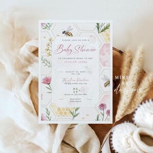 May include: A baby shower invitation with a bee theme. The invitation features a floral and honeycomb design with the text "Baby Shower" and event details. The invitation is surrounded by decorative elements including flowers, bees, and baby shoes.
