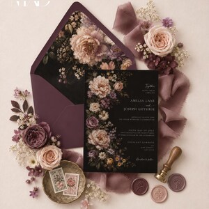 K&ouml;nnte beinhalten: Elegante Hochzeitseinladungssuite mit einer schwarzen Einladungskarte mit floralem Design, einem pflaumenfarbenen Umschlag und dekorativen Elementen wie Briefmarken, Wachssiegeln und B&auml;ndern. Der Einladungstext lautet "Amelia Lane and Joseph Guthrie".