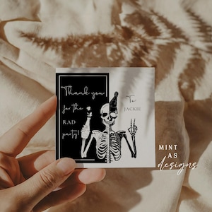 May include: Square, black and white thank you card with a skeleton illustration. The card says "Thank you for the RAD party!" and "To: JACKIE". The card is held by a hand.