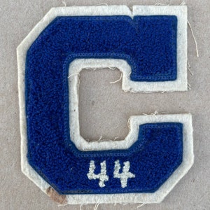 May include: A blue felt letter C with white felt trim and the number 44 in white felt inside the letter.