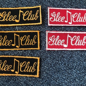 May include: Four embroidered patches with the text "Glee Club" in gold cursive lettering and a musical note. Two patches are black with gold lettering and two patches are red with white lettering.