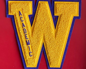 May include: A large yellow felt letter W with a purple felt border. The letter W has the word "ACADEMIC" embroidered vertically down the left side.