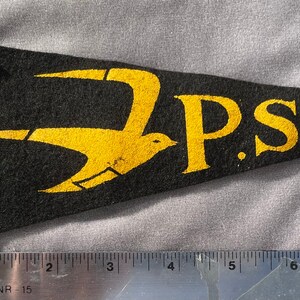 May include: A black felt pennant with a yellow bird design and the text "P.S. 225" in yellow.