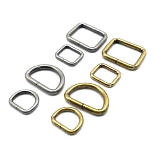 Könnte beinhalten: Sortiment aus silbernen und goldenen D-Ringen und quadratischen Ringen. Die Ringe sind in verschiedenen Größen.