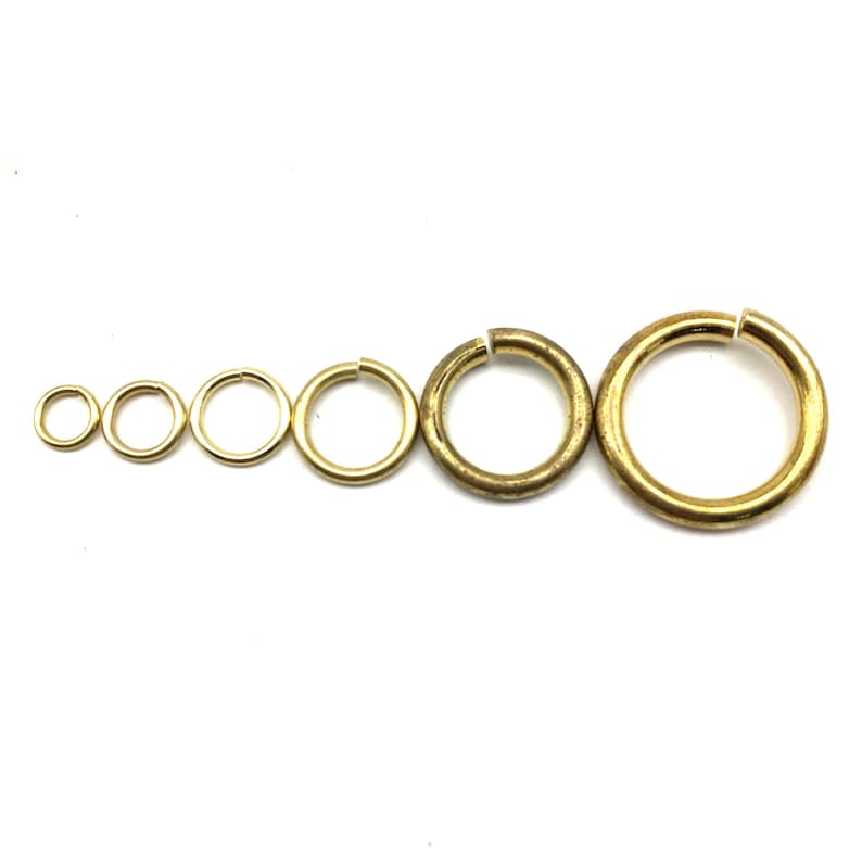 May include: A set of six gold-toned metal jump rings of varying sizes. The rings are arranged in order of size, with the smallest ring on the left and the largest ring on the right.