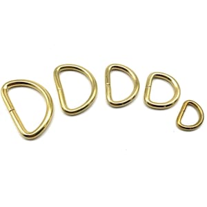 May include: Five gold-toned metal D-rings of varying sizes. The rings are arranged in a semi-circle, with the smallest ring at the bottom right.