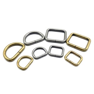 Op de afbeelding: Assortiment van metalen D-ringen en vierkante ringen in gouden en zilveren tinten. De ringen zijn in verschillende maten.
