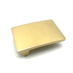 Puede incluir: Una hebilla de cinturón de latón macizo con un acabado liso y pulido. La hebilla es de forma rectangular con bordes redondeados.