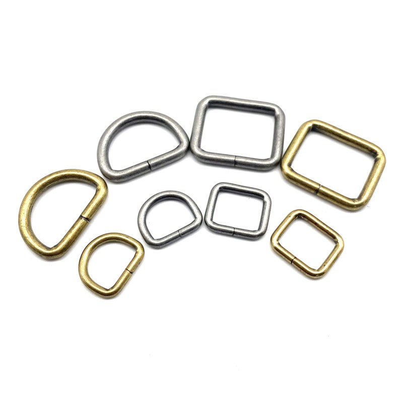 Op de afbeelding: Assortiment van zilveren en gouden metalen D-ringen en vierkante ringen. Deze ringen worden vaak gebruikt om banden, handvatten of andere hardware aan tassen, riemen of andere lederwaren te bevestigen.