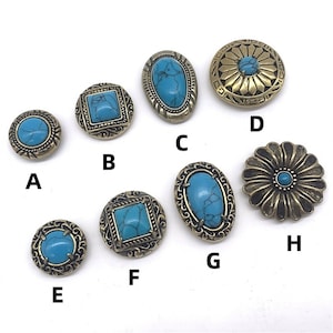 Puede incluir: Diez botones de metal turquesa y dorado con diversas formas y diseños. Los botones están dispuestos en semicírculo sobre un fondo blanco.