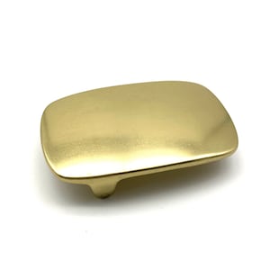 Peut inclure: Une boucle de ceinture en laiton massif avec une finition brossée lisse. La boucle est rectangulaire avec des bords arrondis et présente un design simple et minimaliste.