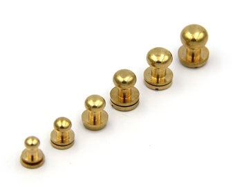 May include: A set of six gold-toned metal knobs of varying sizes. The knobs have a round top and a flat base.