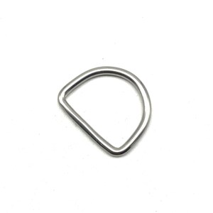 Op de afbeelding: Een zilveren metalen D-ring. Dit type ring wordt vaak gebruikt om banden, riemen of andere accessoires aan te bevestigen.