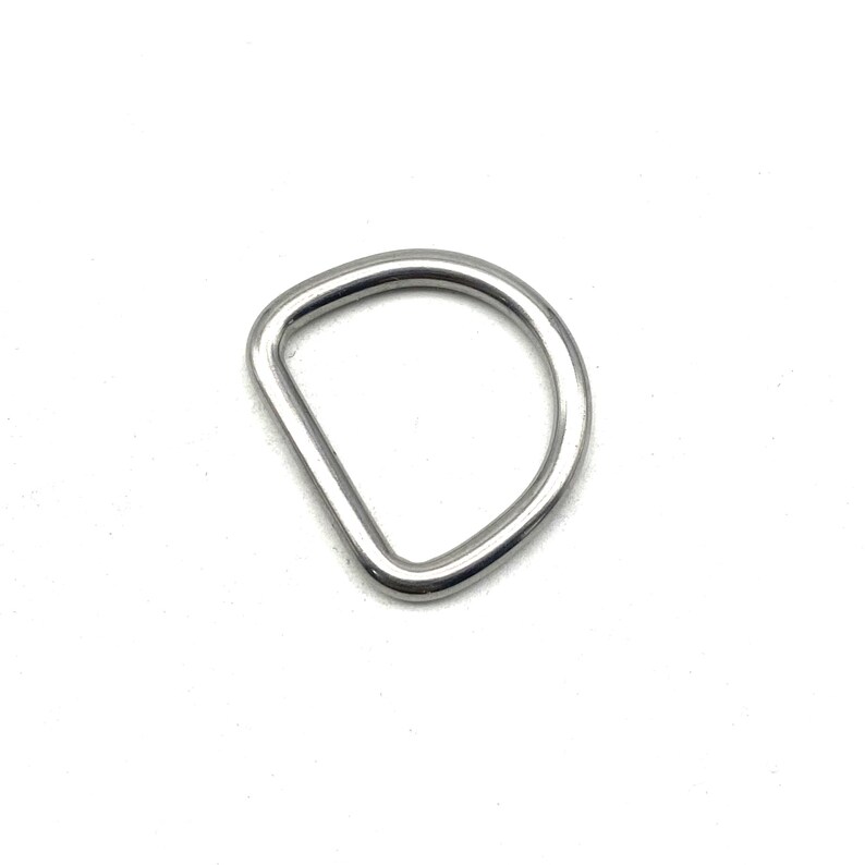 Op de afbeelding: Een zilveren metalen D-ring, een type hardware dat wordt gebruikt om items aan banden, riemen of andere objecten te bevestigen.
