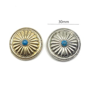 Könnte beinhalten: Zwei runde Metallknöpfe mit einem türkisfarbenen Stein in der Mitte. Die Knöpfe haben ein Sonnenstrahlen-Design und einen seilartigen Rand. Die Knöpfe haben einen Durchmesser von 30 mm.