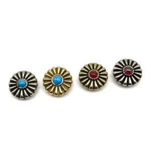 Pode incluir: Quatro botões de metal em forma de flor com pedras preciosas de diferentes cores no centro. Os botões são prateados, dourados, prateados e prateados. As pedras preciosas são turquesa, turquesa, vermelha e vermelha.