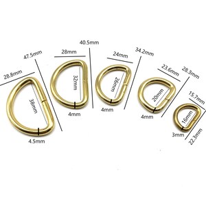 May include: Five gold-colored metal D-rings of different sizes. The rings are measured in millimeters. The smallest ring is 16mm in diameter, and the largest ring is 38mm in diameter.