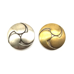 May include: Two round metal buttons with a three-leaf clover design. One button is silver and the other is gold.