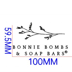 Peut inclure: Dessin au trait noir et blanc d'une branche avec des feuilles. Le texte "BONNIE BOMBS & SOAP BARS&reg;" est sous le dessin. Le texte "100MM" est sous le texte, en bleu.
