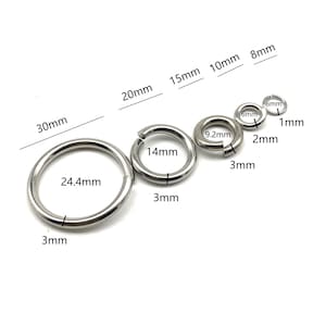 Puede incluir: Surtido de anillos de salto de metal plateado en varios tamaños, que van desde 1 mm hasta 30 mm de diámetro. Los anillos se muestran sobre un fondo blanco.