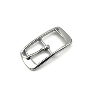 Hebilla de cinturón delgada para mujer con acabado brillante y cierre de correa de cuero.