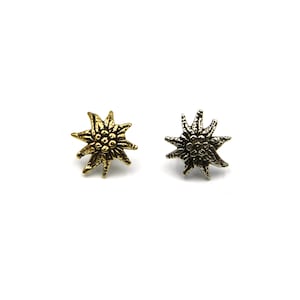 May include: Two edelweiss flower pins, one gold and one silver, with a textured finish.
