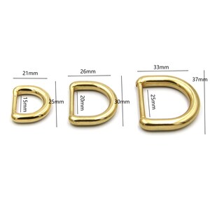 May include: Three gold-toned metal D-rings in different sizes. The smallest ring is 3.8 cm in diameter, the middle ring is 5 cm in diameter, and the largest ring is 6.4 cm in diameter.