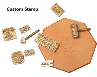 Könnte beinhalten: Ein Satz individueller Messingprägestempel für die Lederverarbeitung. Die Stempel umfassen verschiedene Designs, darunter einen Weihnachtsbaum, ein Blumenmuster, ein Herz und einen Textstempel mit der Aufschrift "Beste Wünsche an dich". Die Stempel sind auf einem Stück braunem Leder angeordnet.