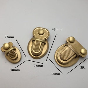 Pode incluir: Três fechos de metal dourado com tamanhos e designs diferentes. O fecho maior mede 4,3 cm por 3,2 cm, o fecho médio mede 2,7 cm por 2,7 cm e o fecho menor mede 1,8 cm por 2,7 cm.