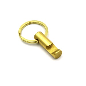 May include: A gold-coloured bottle opener keychain with a round key ring. The bottle opener is attached to the key ring with a metal loop.