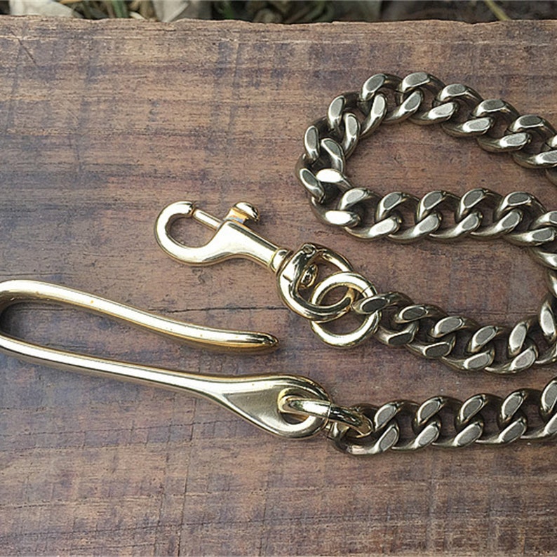 May include: A gold-toned chain with a thick, curb link design. The chain is attached to a gold-toned hook with a swivel clasp.