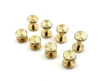 May include: Eight gold-toned metal studs with a decorative, sunburst-like pattern on the top. The studs have a cylindrical base.