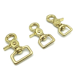 May include: Three gold-toned metal swivel snap hooks. The hooks have a rectangular loop and a spring-loaded gate.