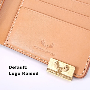 Peut inclure: Un portefeuille en cuir tann&eacute; avec une bordure cousue et un logo en relief qui dit "SUMMER MOOSE".