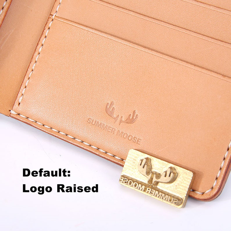 Peut inclure: Un portefeuille en cuir tann&eacute; avec une bordure cousue et un logo en relief qui dit "SUMMER MOOSE".