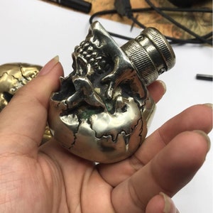May include: A silver skull-shaped gear shift knob with a detailed design. The knob has a threaded metal insert on the top.