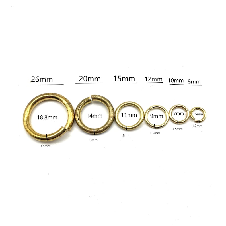 May include: Assortment of 10 gold jump rings in various sizes, ranging from 5.5 mm to 26 mm in diameter. The jump rings are arranged in order of size, with the smallest ring on the right and the largest ring on the left.