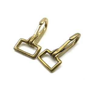 May include: Two brass swivel snap hooks with a square loop. The hooks are a gold color and have a shiny finish.