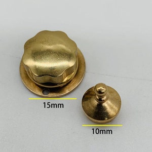 Puede incluir: Dos piezas de ferretería de latón. La pieza más grande es una base redonda de 3,8 cm de diámetro con una perilla en forma de estrella de 7 puntas en la parte superior. La pieza más pequeña es una base redonda de 2,5 cm de diámetro con una perilla redonda en la parte superior.