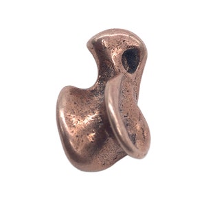 Könnte beinhalten: Eine kleine, abstrakte, kupferfarbene Metallskulptur mit einem Loch oben. Die Skulptur ist wie ein Vogel mit ausgebreiteten Flügeln geformt.
