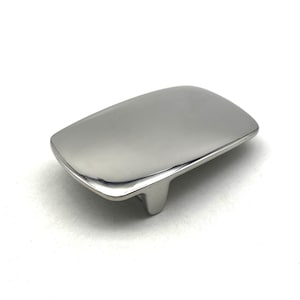 Puede incluir: Una hebilla de cinturón de metal plateado con una superficie lisa y redondeada.