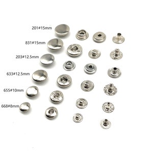 Puede incluir: Surtido de botones a presión de metal plateado en varios tamaños. Los tamaños están etiquetados como 201#15mm, 831#15mm, 203#12.5mm, 633#12.5mm, 655#10mm y 668#8mm.