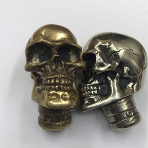 May include: Two decorative skull-shaped bottle stoppers. One is gold and the other is silver.